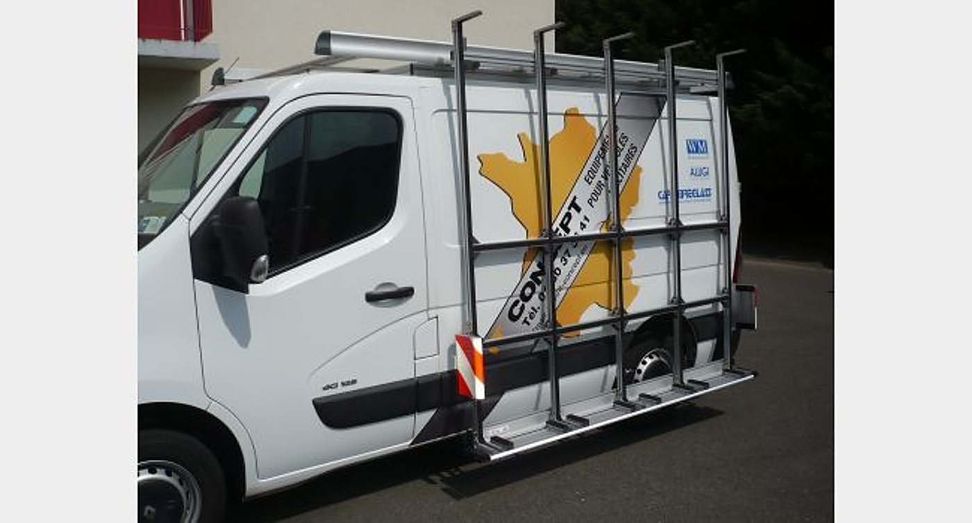 Une camionnette utilitaire blanche équipée d'un support à vitres métallique sur le flanc, avec un logo jaune en forme de carte de France et le nom Concept.